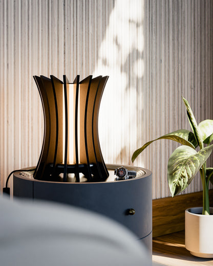 Gothica table lamp in black walnut veneered wood sculptural modern design, placed in a minimalist modern bedroom. Warm led light.