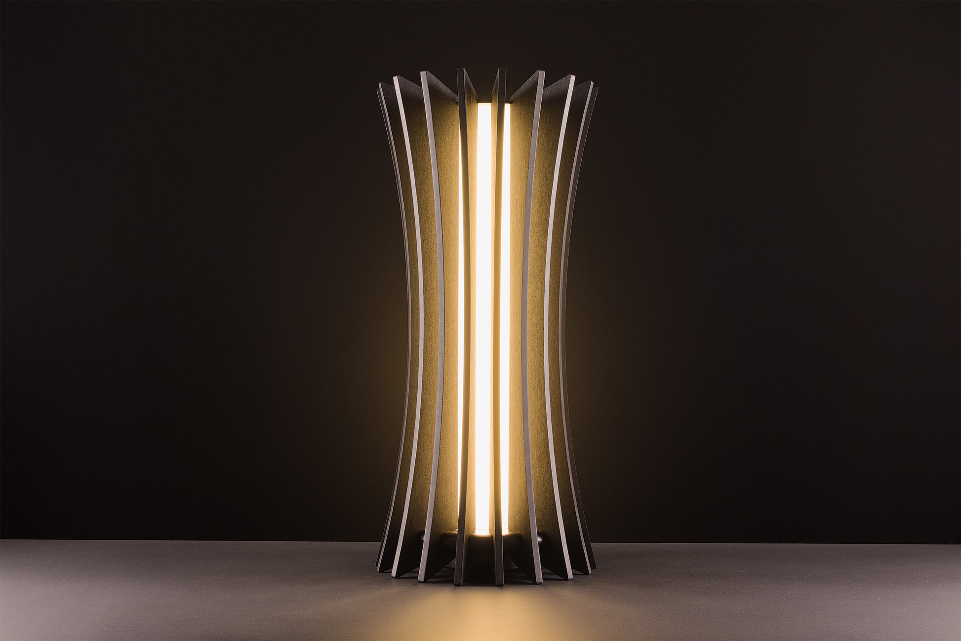 Vertigo table lamp in dark stained walnut, handcrafted Italian design, sculptural minimal style, refined elegance, warm light, studio black background.