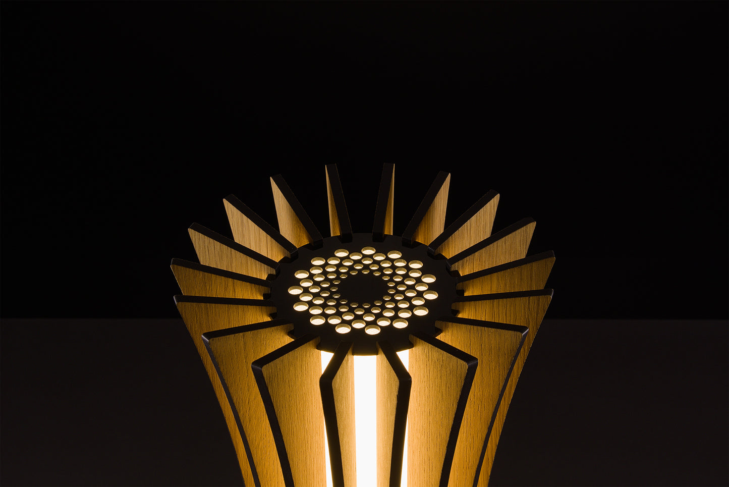 Handmade Vertigo lamp in natural oak veneer, Italian design excellence, soft warm LED glow, studio black backdrop.