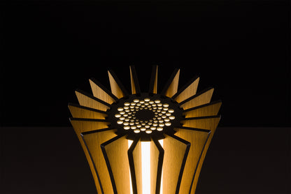 Handmade Vertigo lamp in natural oak veneer, Italian design excellence, soft warm LED glow, studio black backdrop.